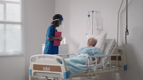 An-elderly-white-man-of-60-70-years-old-is-lying-in-a-hospital-bed-talking-to-a-black-woman-doctor.-Discussion-of-treatment-with-a-cardiologist-neurologist.-Rehabilitation-plan-after-recovery